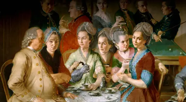 En grupp människor samlas runt ett bord för att dricka kaffe, en scen som speglar kaffets historia och dess sociala betydelse.