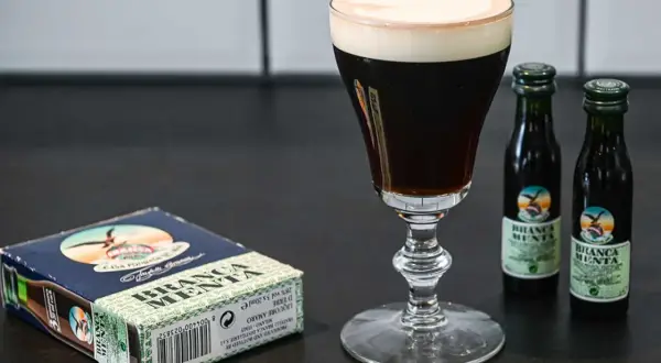 En elegant kaffedrink med krämig topping, bredvid en ask och två små flaskor Branca Menta.