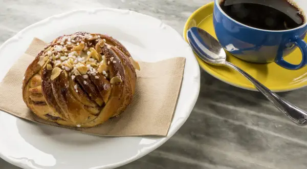 En kanelbulle med pärlsocker och mandelspån, perfekt till en kopp svensk kaffe.