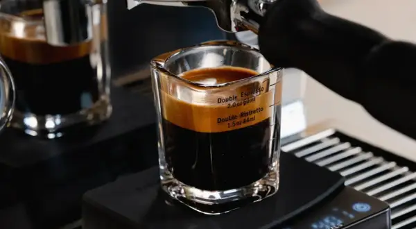A double ristretto and double espresso in a glass shot with measurement markings.