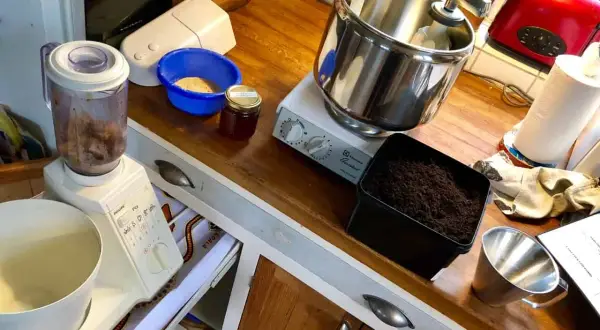 Förbereder för att mala tobak till snus. Köksbänk med mixer, skål med tobak, burk med honung och en köksmaskin.