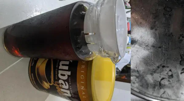 En stor glasburk med kondens fylld med mörkt, gammalt kaffe står bredvid en gul burk med "ubán Gold" kaffe.