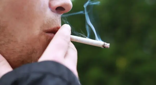 En person röker en cigarett med mentolsmak utomhus i Sverige.