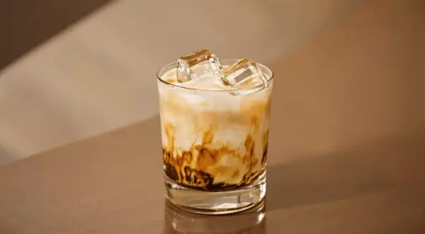 En glas med freddo cappuccino, is och mjölk som virvlar i en vacker marmorering. Perfekt för en varm sommardag.