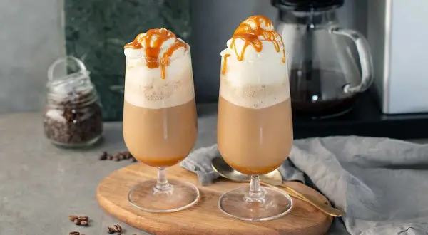 Två glas med krämig frappe caramel, toppade med vispgrädde och karamellsås. Perfekt för en fika.