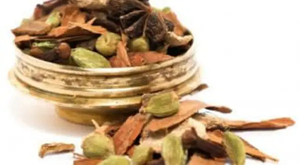 En gyllene skål fylld med en aromatisk chai kryddblandning: kanel, kardemumma, stjärnanis och nejlikor.