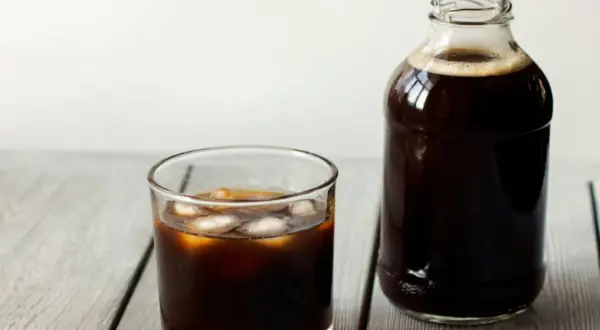 Ett glas islat kaffe bredvid en flaska med kallbryggt kaffe. Perfekt för ett enkelt cold brew recept.