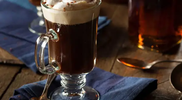 En värmande irish coffee med rom, toppad med fluffigt grädde och en nypa kanel. Perfekt för en mysig kväll.