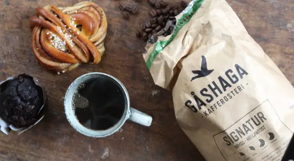 En kanelbulle, chokladmuffin och en kopp kaffe. Perfekt för en **fika paus** med kaffebönor och en påse Gåshaga Kafferosteri.
