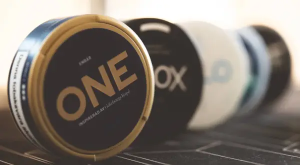 En dosa ONE, inspirerad av Göteborgs Rapé, en av sveriges mest sålda snus. Flera dosor i bakgrunden.