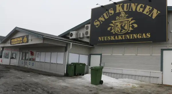 SnusKungen, the king of snus, med sitt gyllene emblem och text på fasaden. En restaurang finns till vänster.
