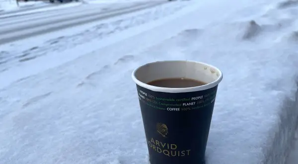En kopp kaffe från Arvid Nordquist står i snön. Undrar vad kostar en kopp kaffe hemma? En varm dryck i vinterkylan.
