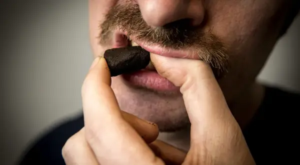 Man med mustasch placerar en prilla snus, kanske det dyraste snuset, i munnen.