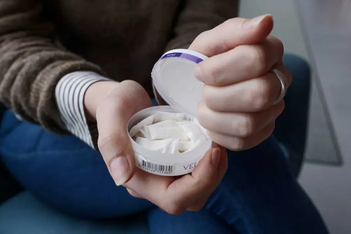 Händer som håller en dosa snus. En kvinna tar fram en prilla ur dosan.