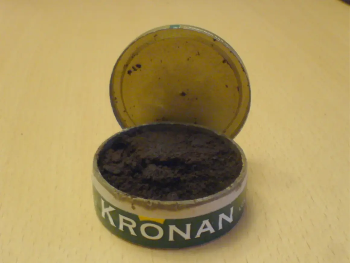 En öppen snusdosa med snus. Kronan-loggan syns tydligt. En klassisk snusdosa storlek.