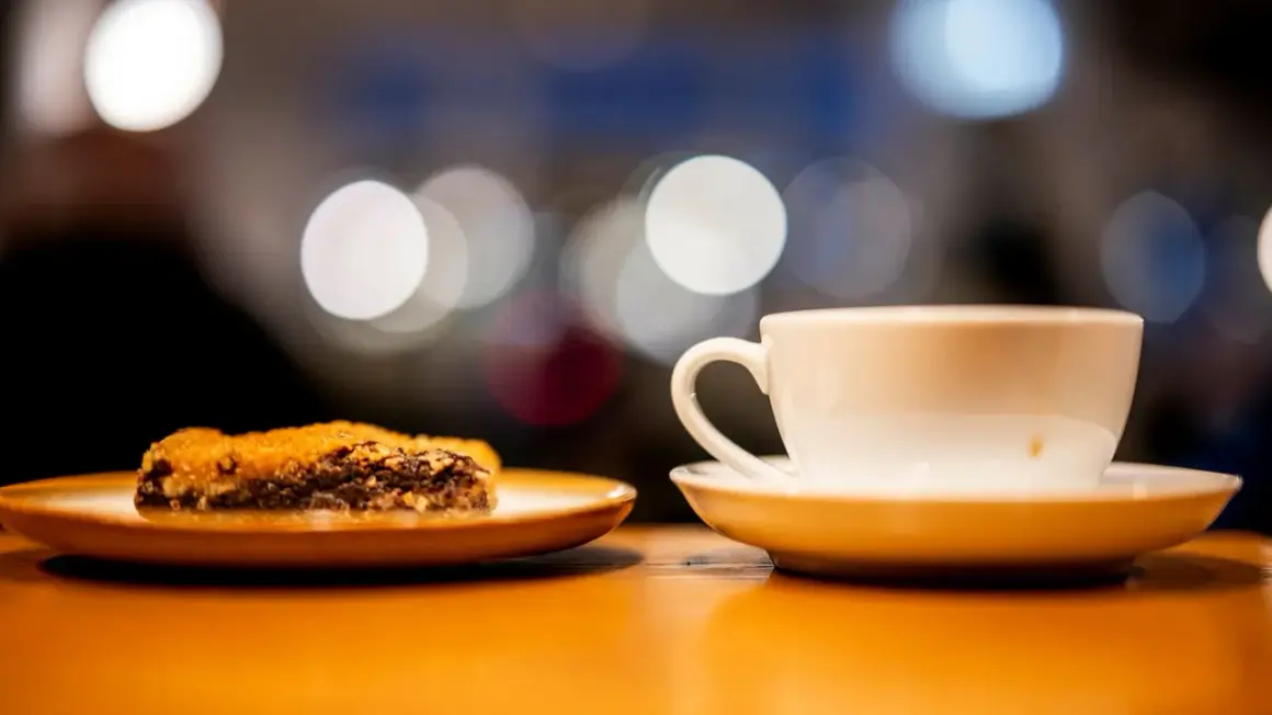 En vit kaffekopp och en bit chokladkaka på ett fat. Perfekt för en fika, en synonym för njutning.