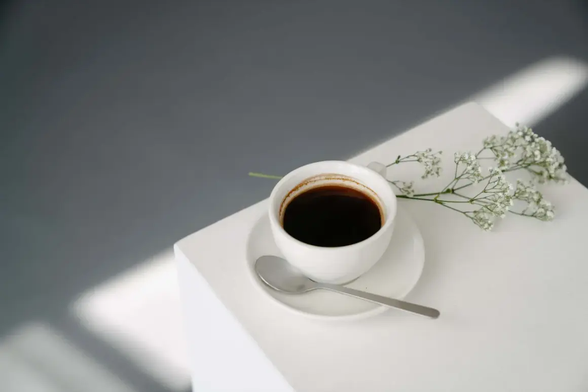 En kopp svart kaffe med en sked och en liten blomsterkvist. Perfekt för en stunds avkoppling med kaffe efter maten.