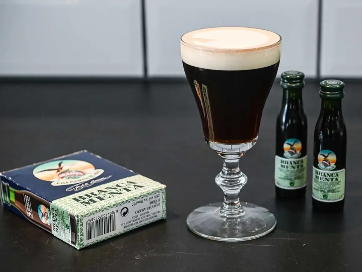 En elegant kaffedrink med krämig topping, bredvid en ask och två små flaskor Branca Menta.