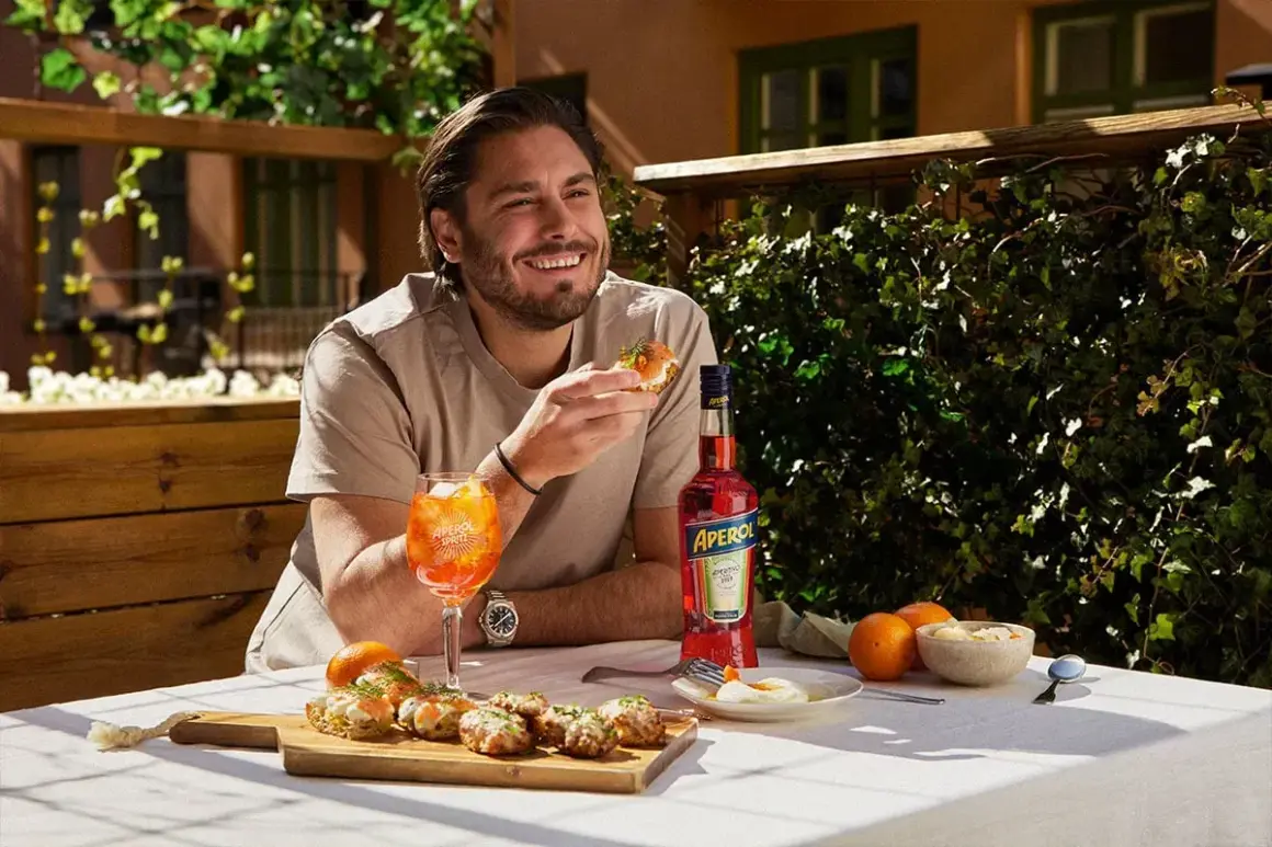 Man njuter av en solig stund med en läcker alkoholfri kaffedrink, tilltugg och en flaska Aperol.