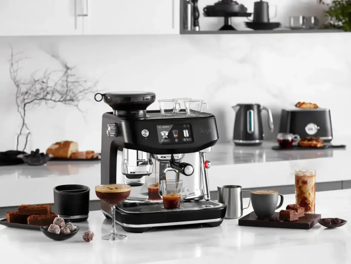 Snygg espressomaskin med inbyggd kvarn, som förbereder vanligt kaffe. Bredvid står godsaker och en kaffekopp.