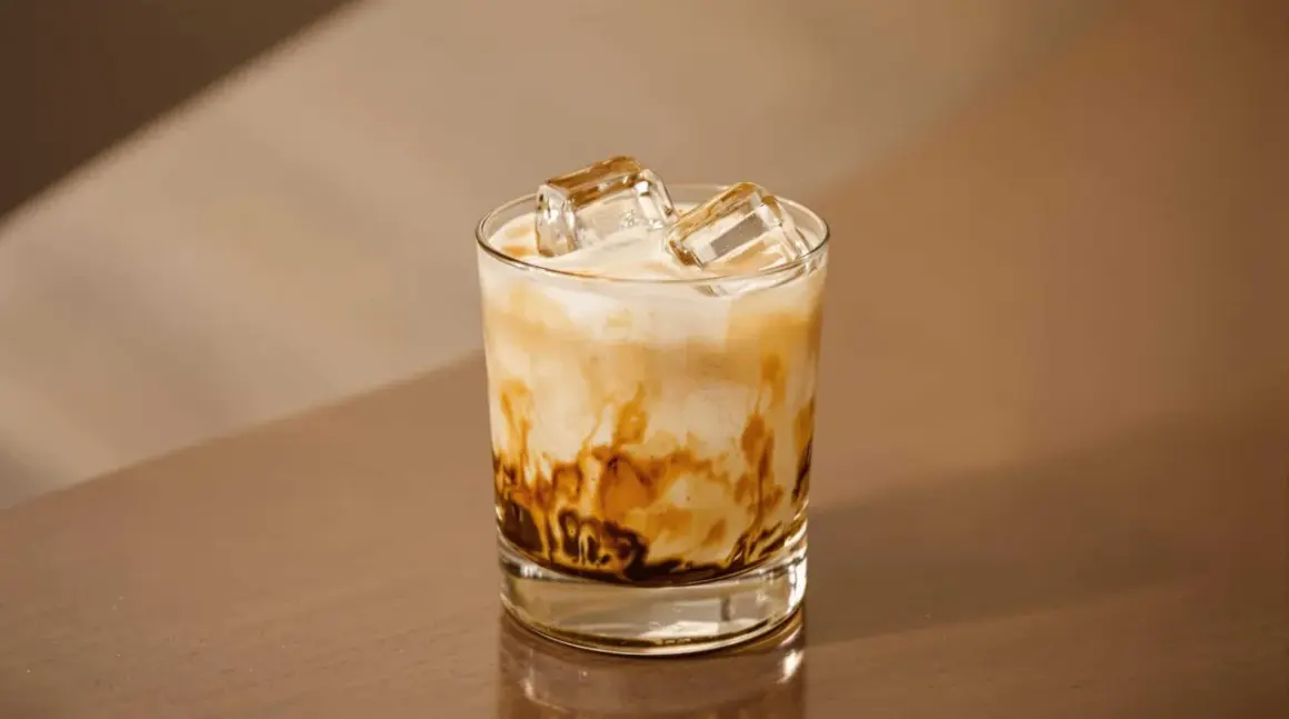 En glas med freddo cappuccino, is och mjölk som virvlar i en vacker marmorering. Perfekt för en varm sommardag.