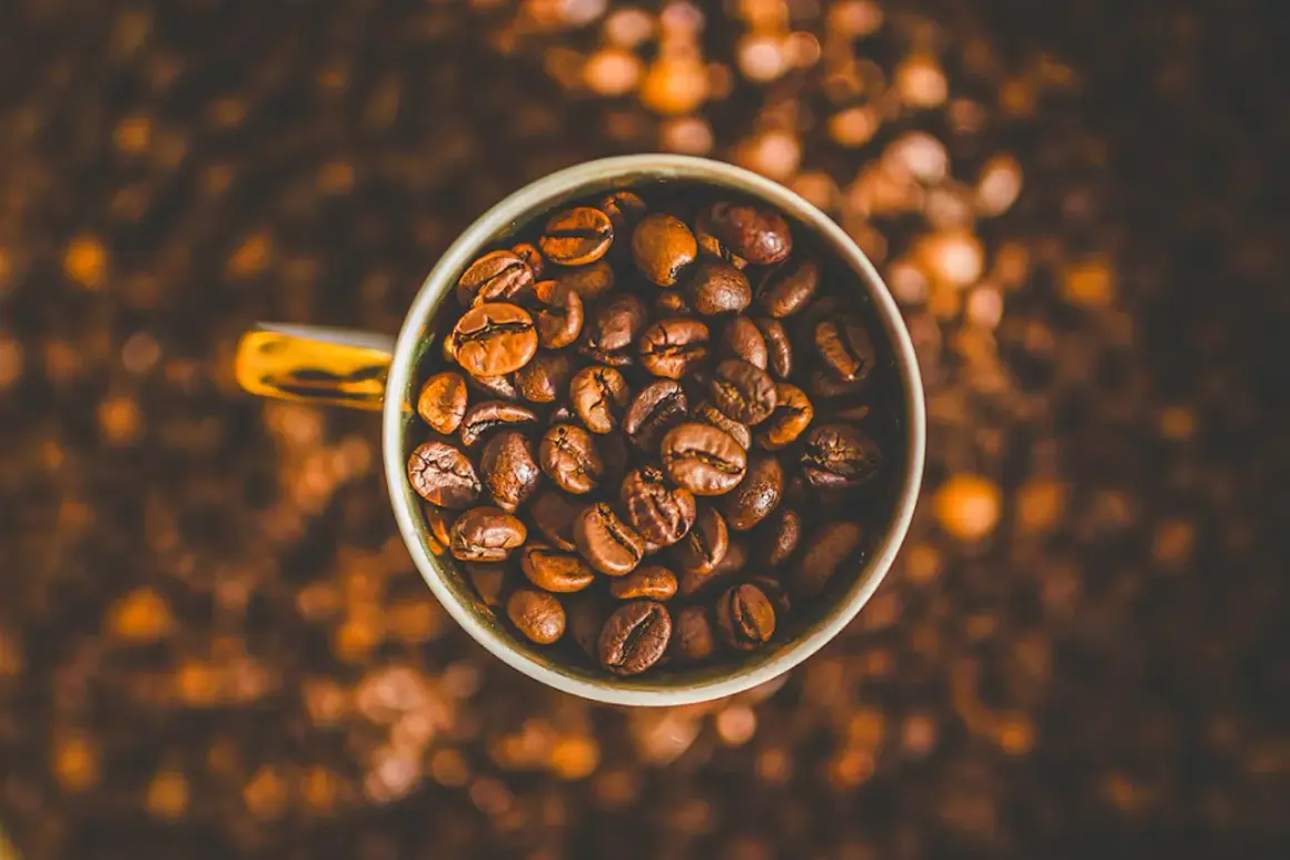 En kopp fylld med kaffebönor, redo att bli en härlig dryck. Kanske en liten barnkopp för en lekfull fika?