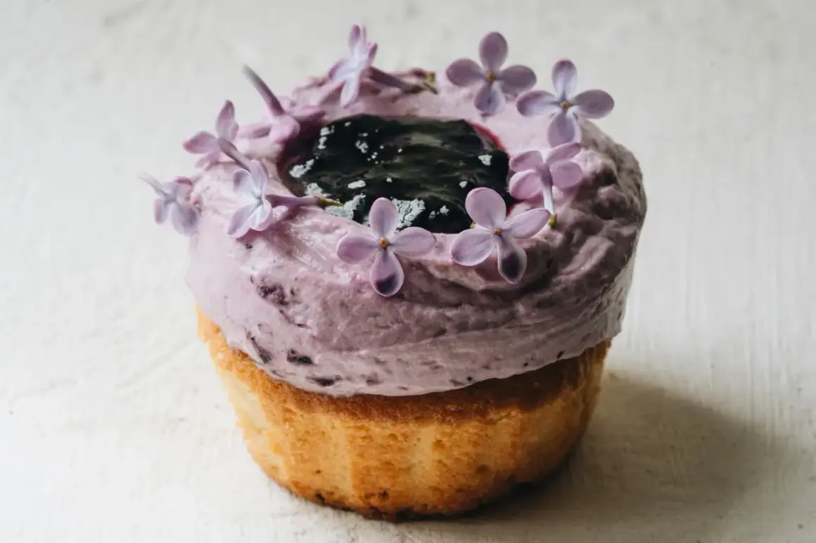 En lila cupcake med blåbärsfrosting, mörka bär och syrenblommor. Ett recept inspirerat av Starbucks.