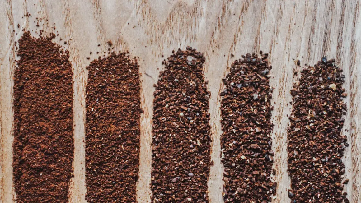 Fem ränder av kaffepulver visar olika malningsgrad, från fint till grovt. Perfekt för att välja rätt malningsgrad kaffe för din bryggmetod.