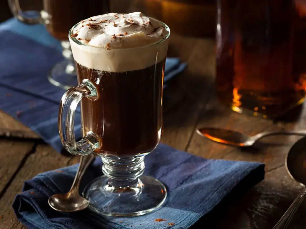 En värmande irish coffee med rom, toppad med fluffigt grädde och en nypa kanel. Perfekt för en mysig kväll.