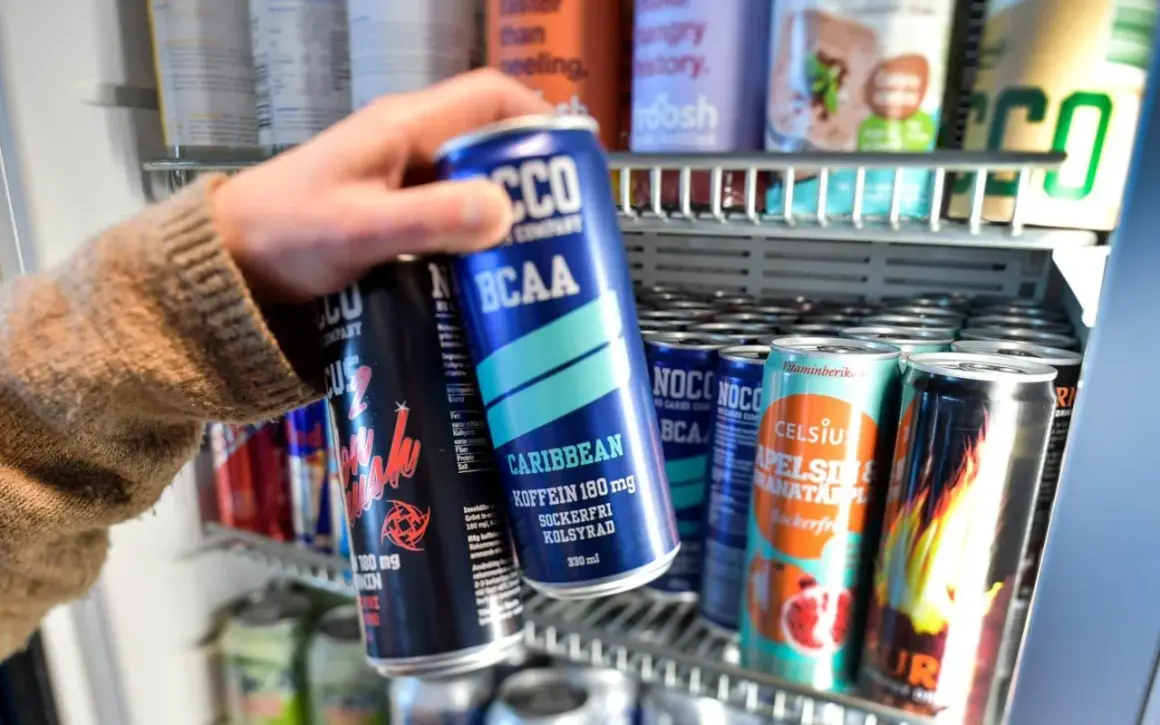Hand tar en energidryck ur ett kylskåp. Frågan om att dricka energidryck gravid är relevant.