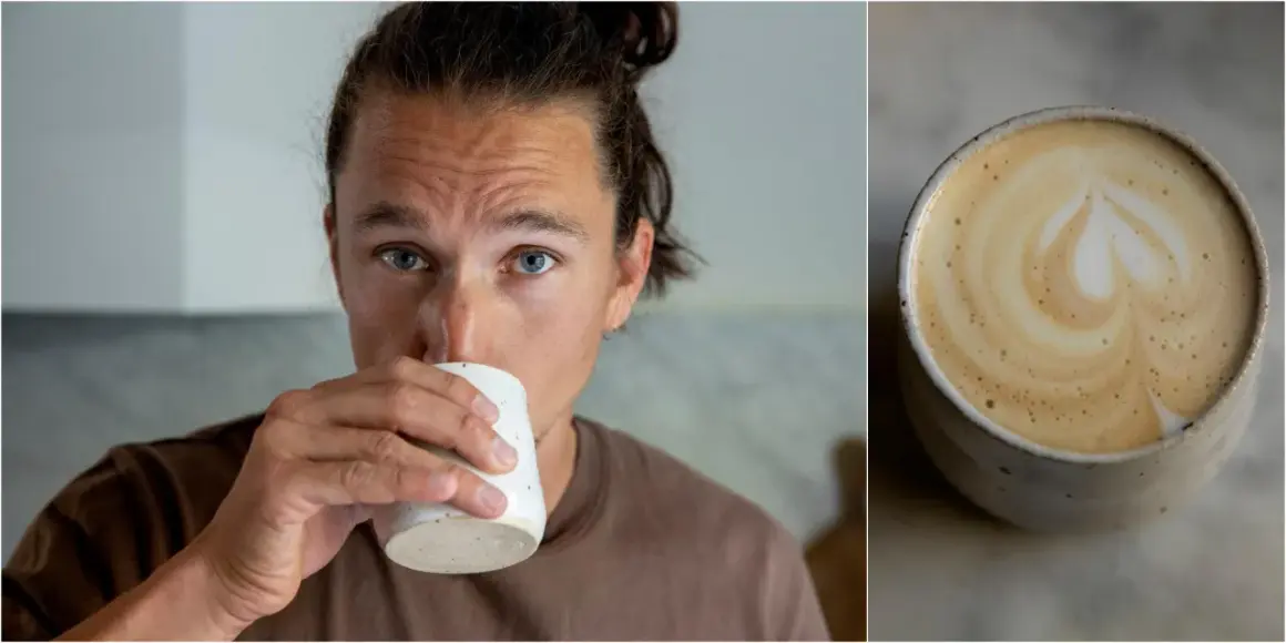 Man med blå ögon dricker en vacker latte hemma. Kaffet har ett hjärtformat mönster i skummet.