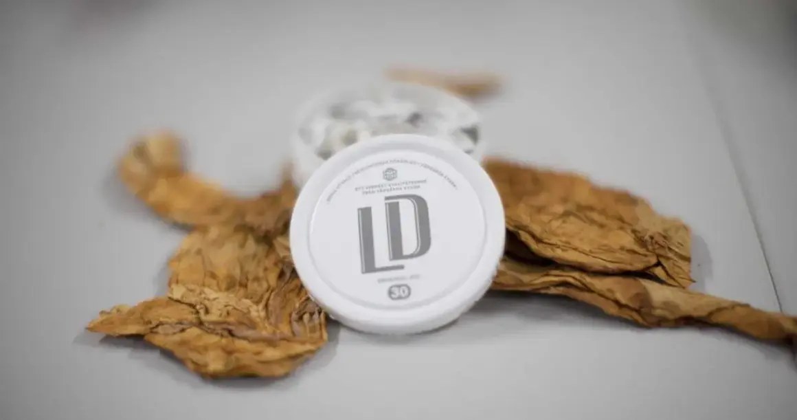 En dosa LD snus ligger på torkade tobaksblad, en del av snus tillverkning.