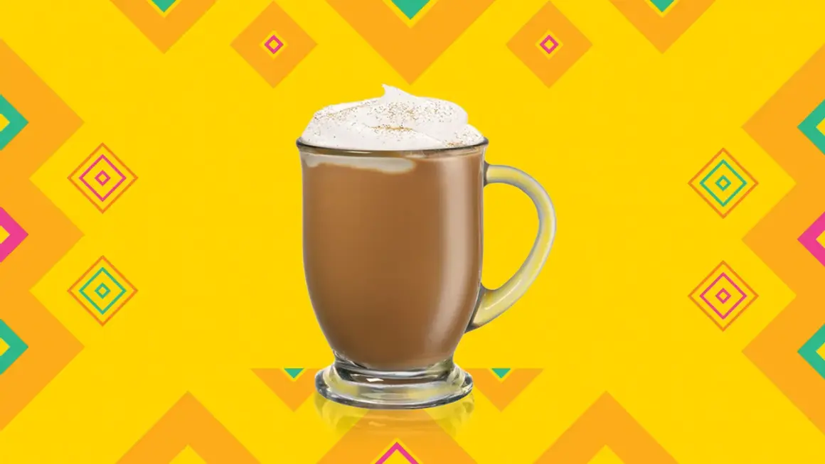 En krämig kaffedrink med kahlua, toppad med vispgrädde och kanel, mot en färgglad bakgrund.