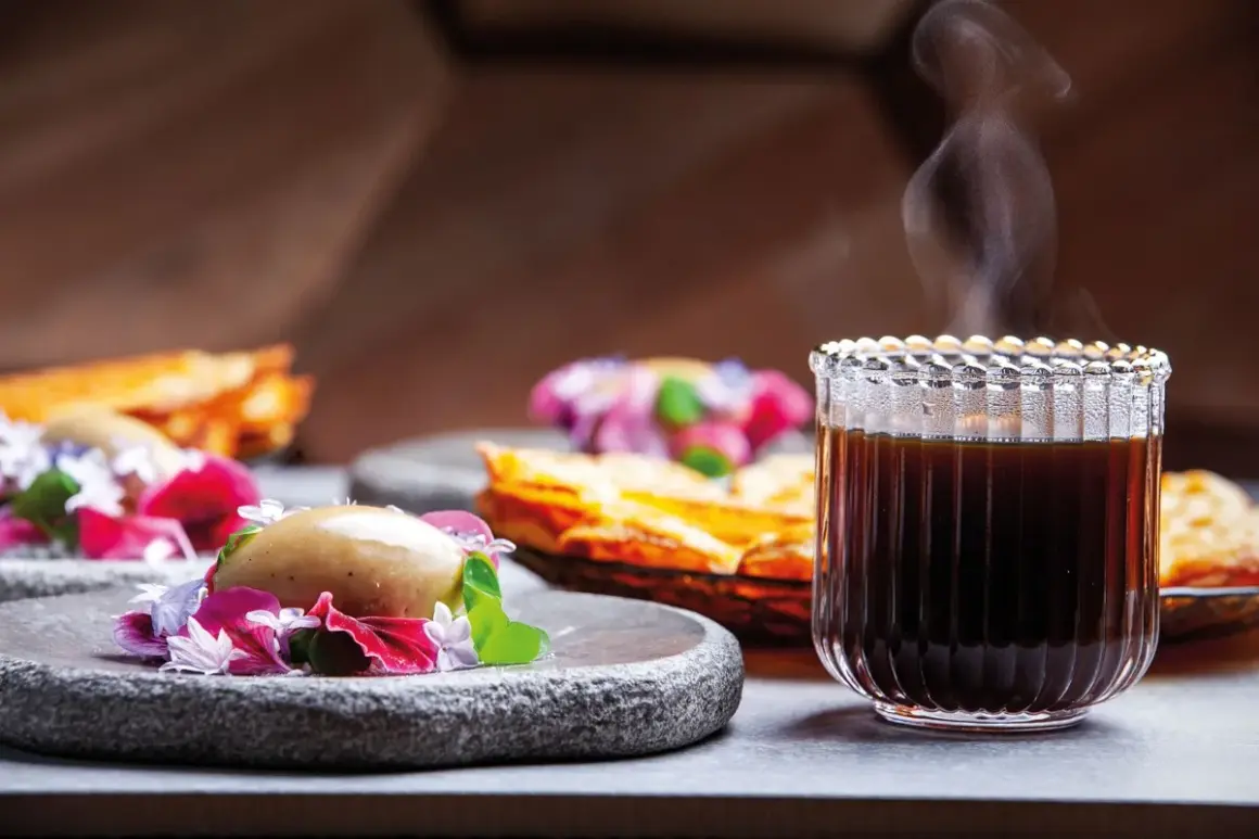 En ångande kopp kaffe glass serveras med en elegant dessert.