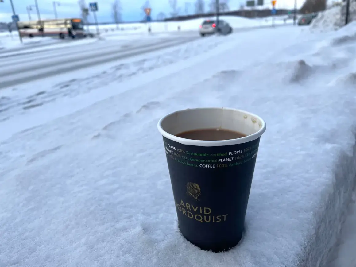 En kopp kaffe från Arvid Nordquist står i snön. Undrar vad kostar en kopp kaffe hemma? En varm dryck i vinterkylan.