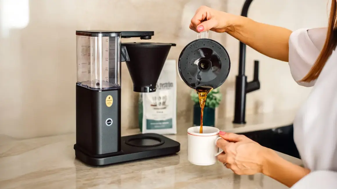 En kaffebryggare som visar hur fungerar en kaffebryggare, med nybryggt kaffe som hälls upp i en mugg.