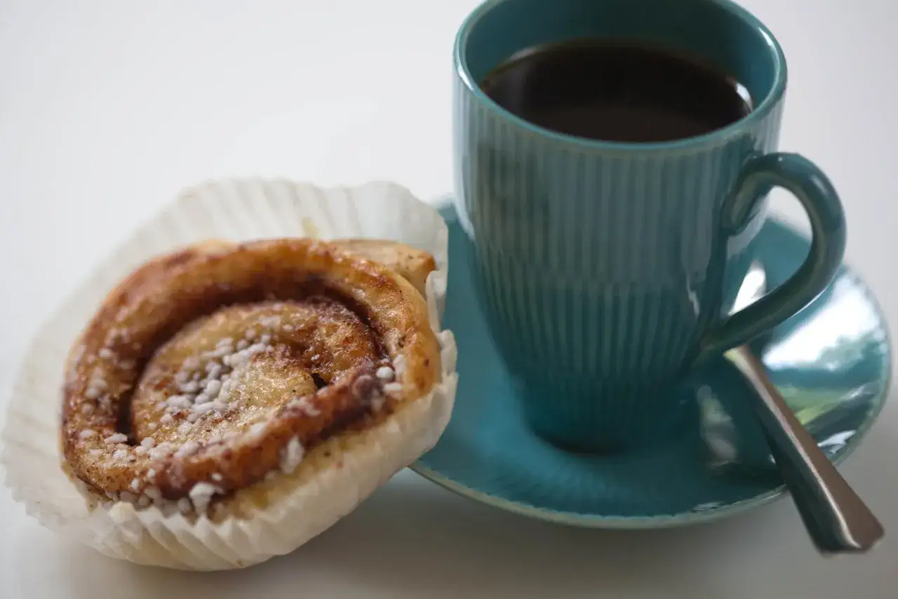 Kanelbulle och en kopp kaffe. Kaffet ser lite svagt ut, kanske är det dåligt kaffe idag.