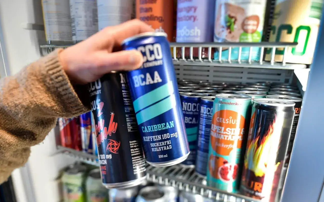 Hand tar en energidryck ur ett kylskåp. Frågan om att dricka energidryck gravid är relevant.