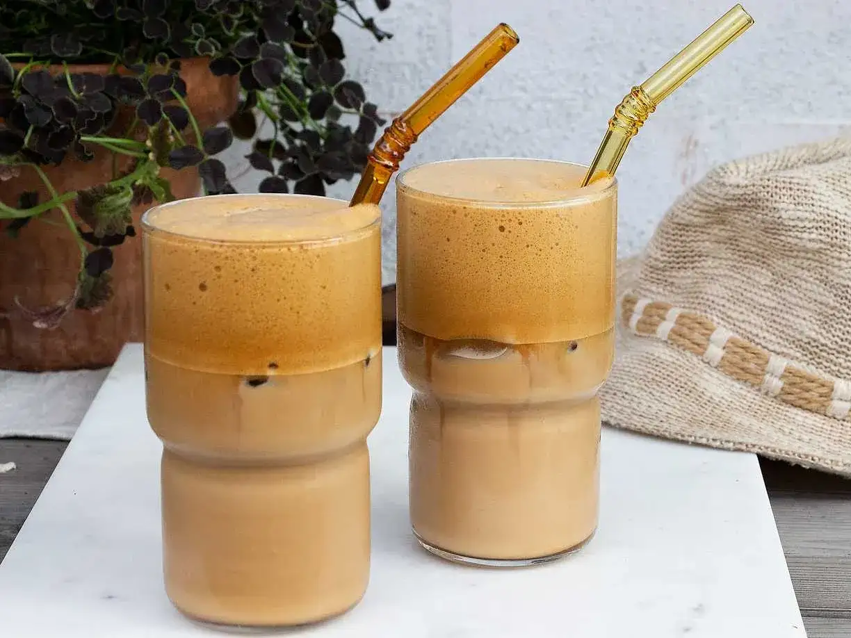 Två glas med grekisk frappe, is och skummigt kaffe. En solig dag i Grekland.