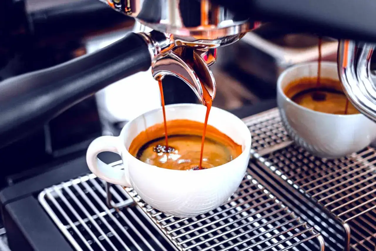 Enkel espresso rinner ner i en vit kopp från en espressomaskin.