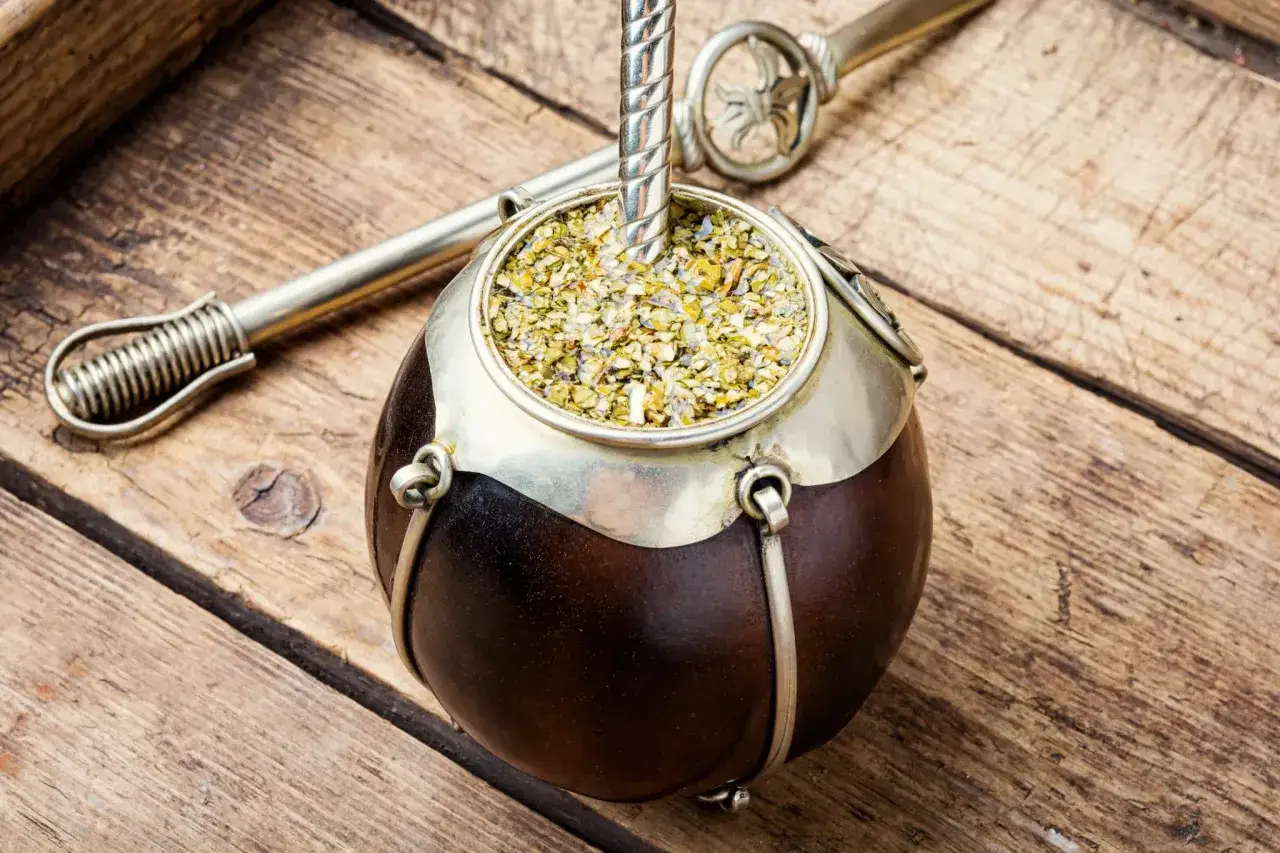 En traditionell kalebass med mate drink och bombilla på träbord.
