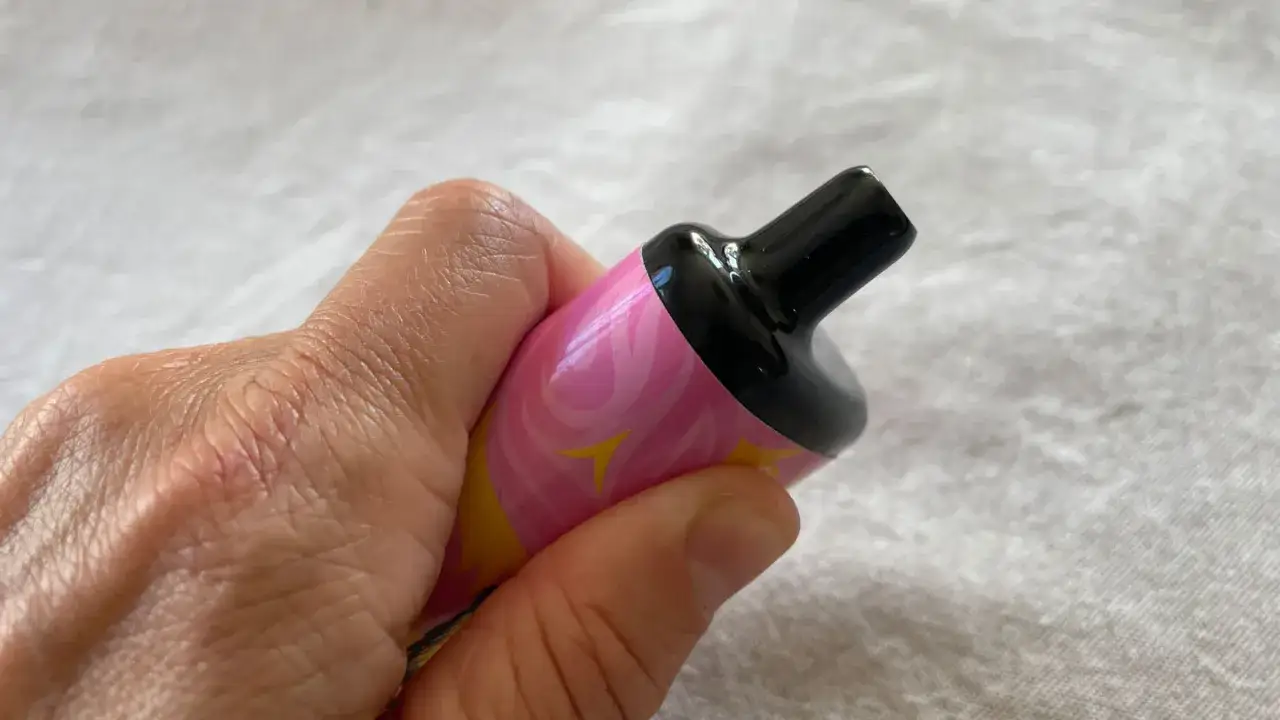 En hand håller en färgglad vape med rosa och gula mönster. Ett modernt alternativ till cigg.