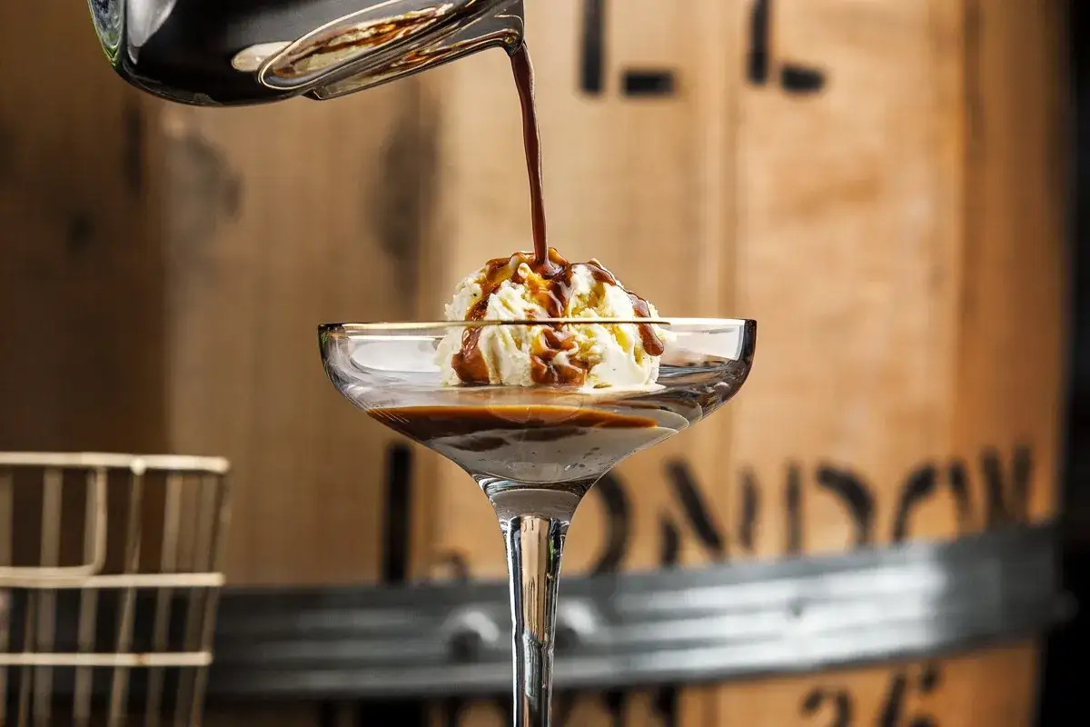 Varm espresso hälls över vaniljglass i ett elegant glas. En perfekt cafe affogato.