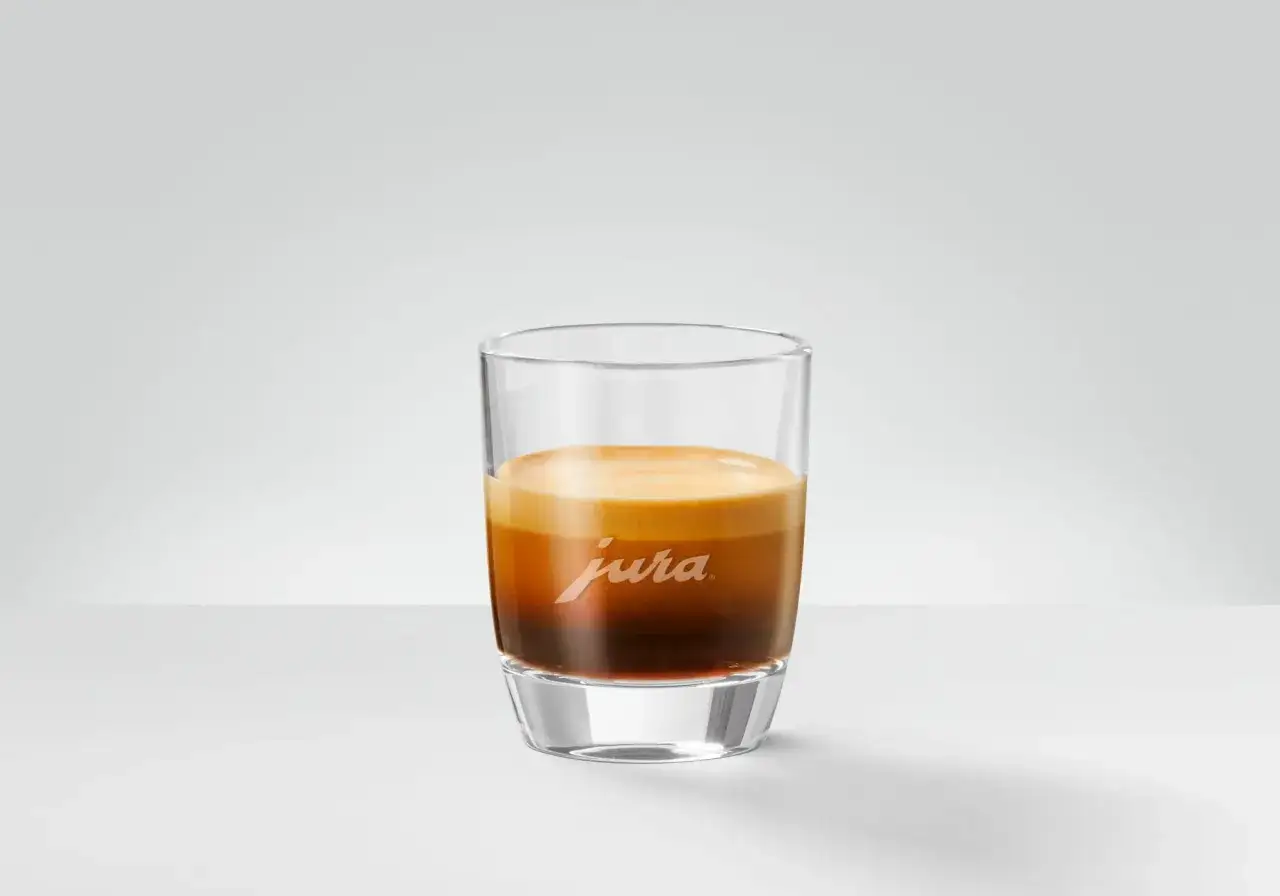 En perfekt espresso ristretto med gyllene crema i ett glas med Jura-logotyp.