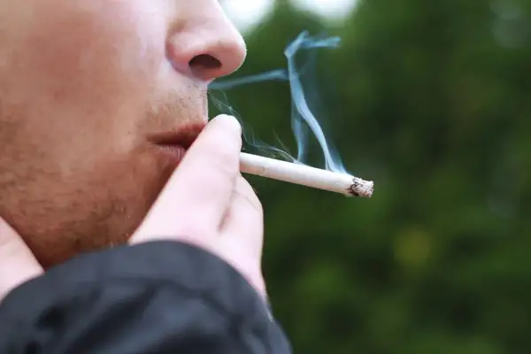 En person röker en cigarett med mentolsmak utomhus i Sverige.