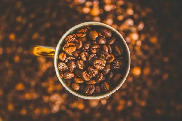 En kopp fylld med kaffebönor, redo att bli en härlig dryck. Kanske en liten barnkopp för en lekfull fika?